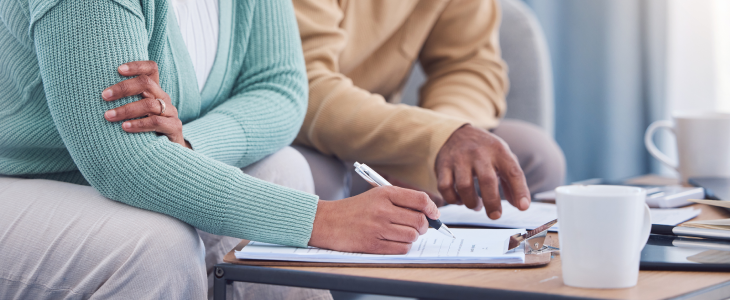 Wife and husband signing a will during their estate planning process.